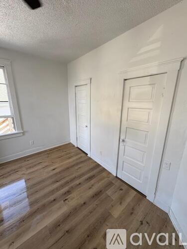 A room with wooden flooring and two white doors.
