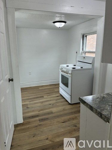 A kitchen with a white stove and wooden floors.
