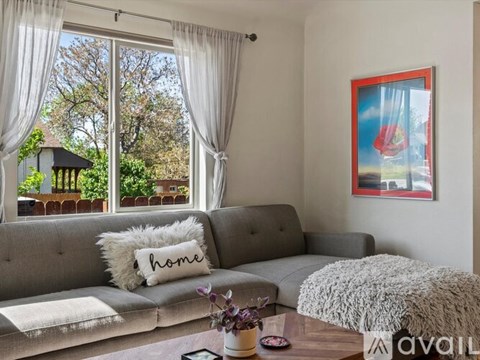 A living room with a grey couch and a pillow that says home.