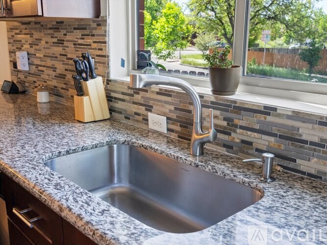 A kitchen sink with a granite countertop and a silver faucet.