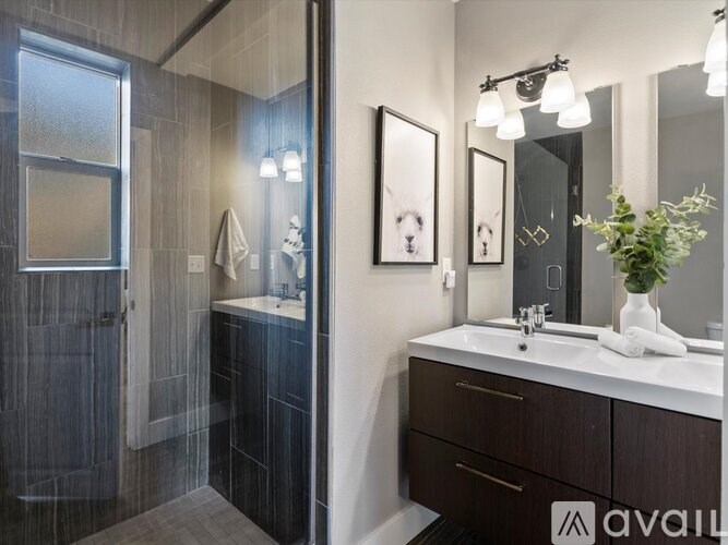 A bathroom with a sink, mirror, and shower.