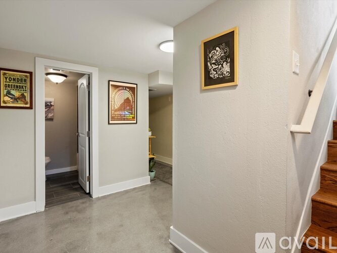 A hallway with a staircase on the right and a door on the left.