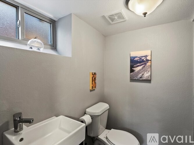 A bathroom with a toilet, sink, and a window.
