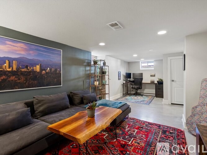 A living room with a grey couch, a wooden coffee table, and a large landscape painting on the wall.