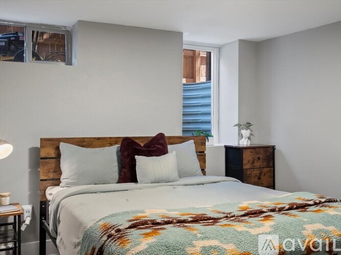 A bedroom with a bed, pillows, and a wooden headboard.