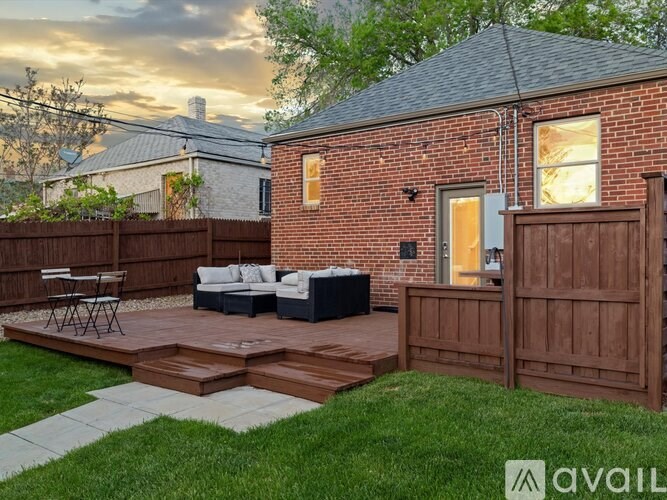 A backyard with a brick building, a wooden fence, and a patio area.