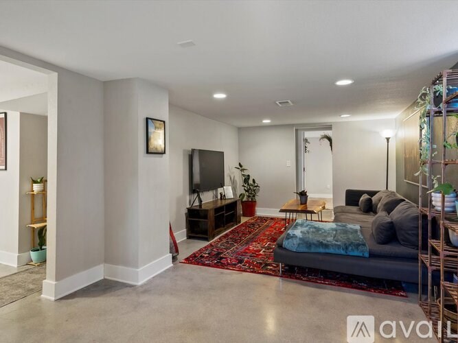 A living room with a grey sofa and a red rug.