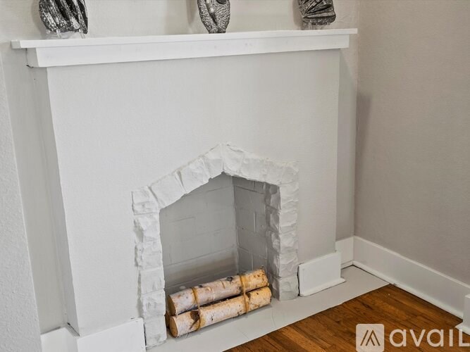 A white fireplace with logs inside it.