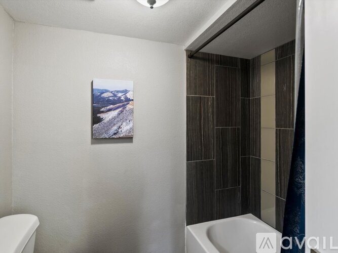 A bathroom with a toilet, a sink, and a picture of a mountain landscape on the wall.