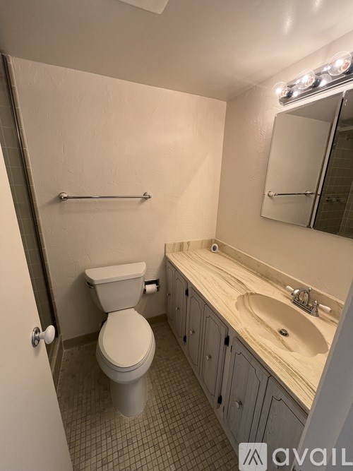 A bathroom with a toilet, sink, and mirror.