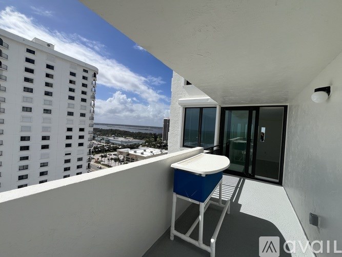 A balcony with a blue and white chair overlooks a cityscape.