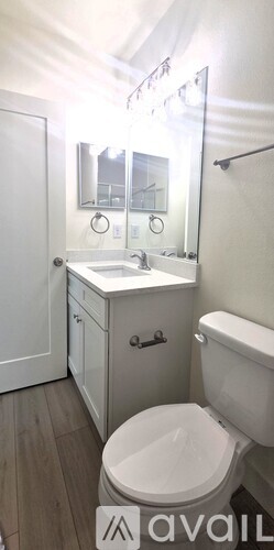 A bathroom with a toilet, sink, and mirror.