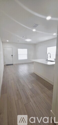 A spacious room with wooden flooring and white walls.