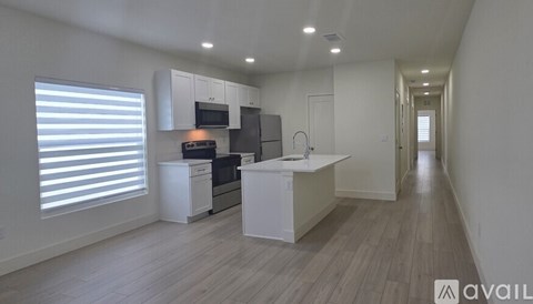 A modern kitchen with white cabinets and a wooden floor.