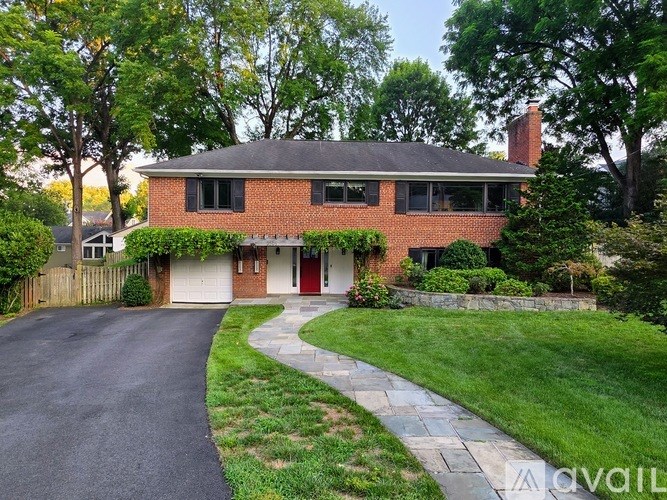 A red brick house with a black roof and a red door.