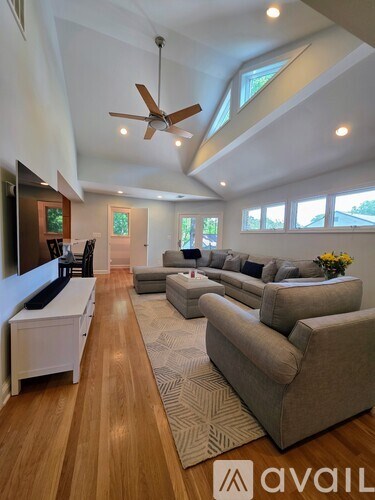 A spacious living room with a long couch and a ceiling fan.