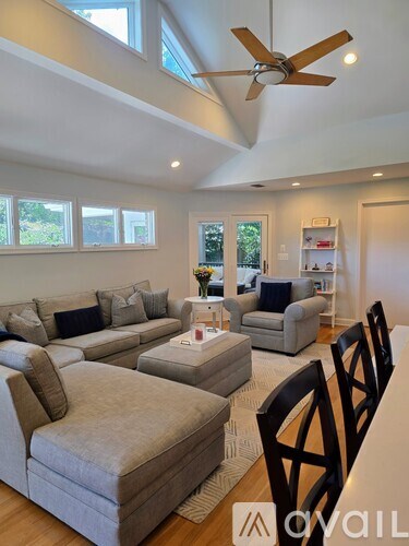 A living room with a grey sofa and a fan.