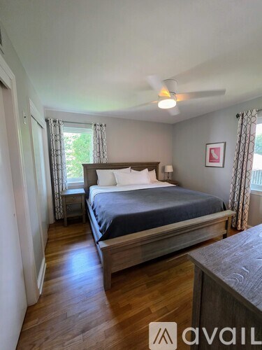 A bedroom with a bed, wooden floors, and a ceiling fan.