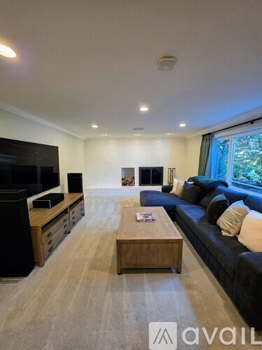 A living room with a black couch and a wooden coffee table.