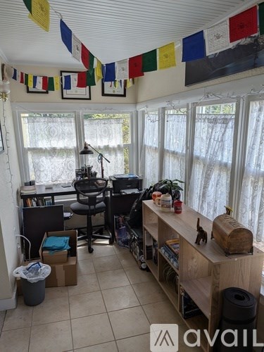 A room with a desk, chair, and flags hanging from the ceiling.