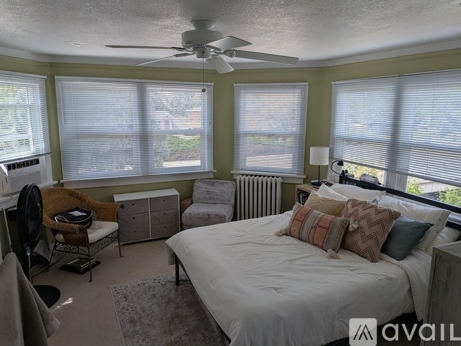 A bedroom with a bed, chair, and window with blinds.