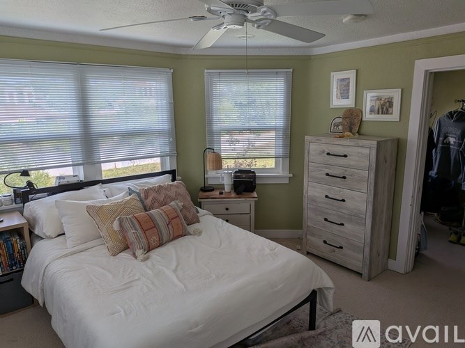 A bedroom with a bed, dresser, and window with blinds.