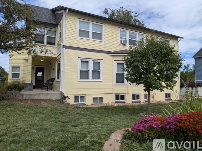 A two-story house with a front porch and a tree in the front yard.