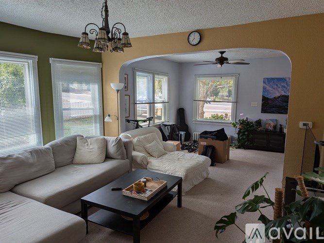 A living room with a white couch, a black coffee table, and a ceiling fan.