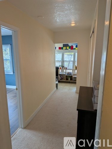 A hallway with a carpeted floor and a door on the left.