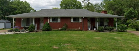 A red brick house with a grey roof and a white door.
