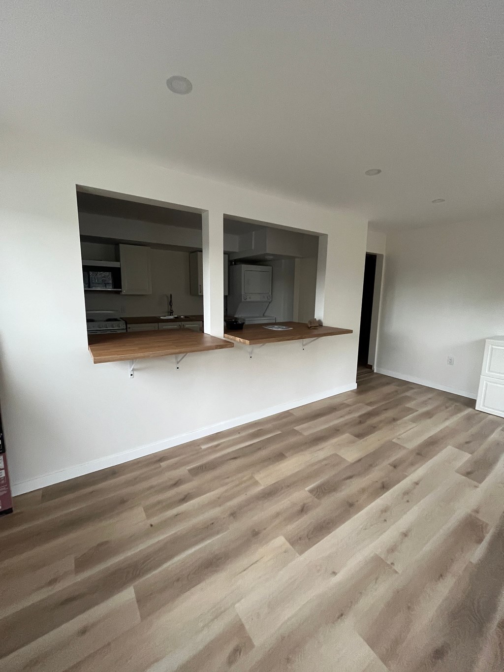 A room with wooden flooring and two windows.