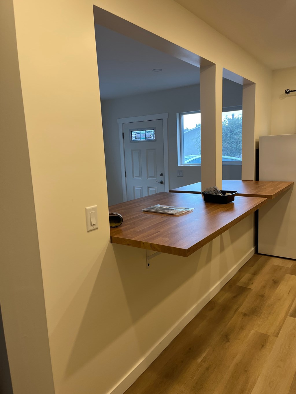 A white wall with a light switch and a wooden counter.