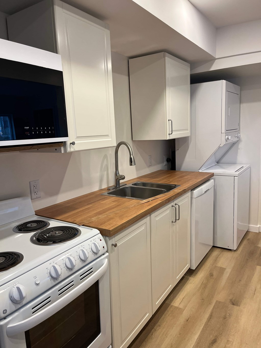 A kitchen with white cabinets and a wooden countertop.