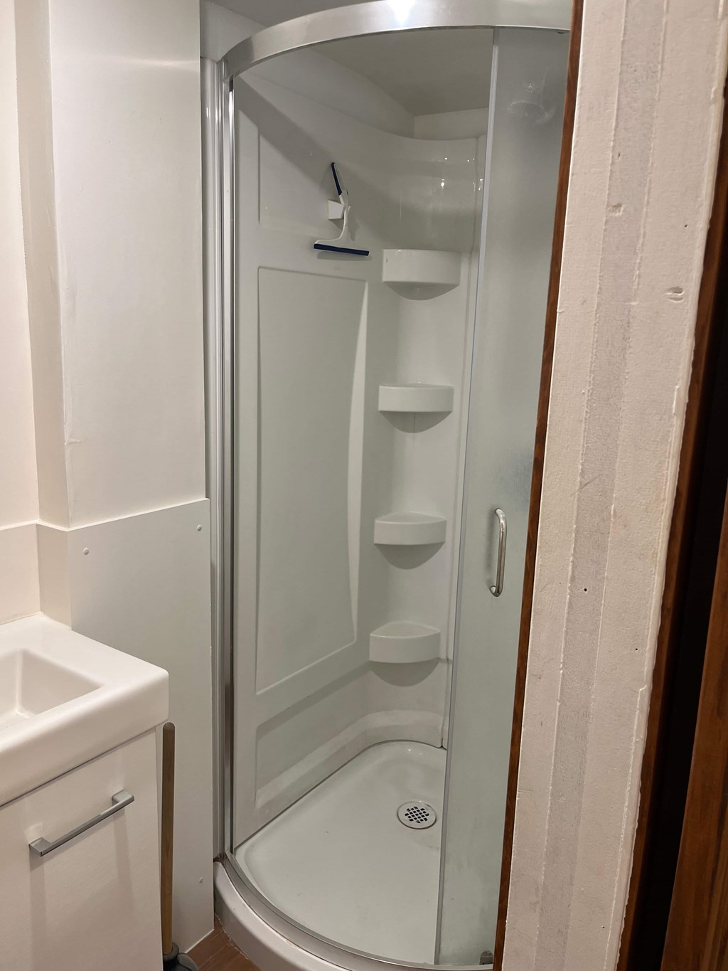 A white shower stall with a glass door and a white toilet next to it.