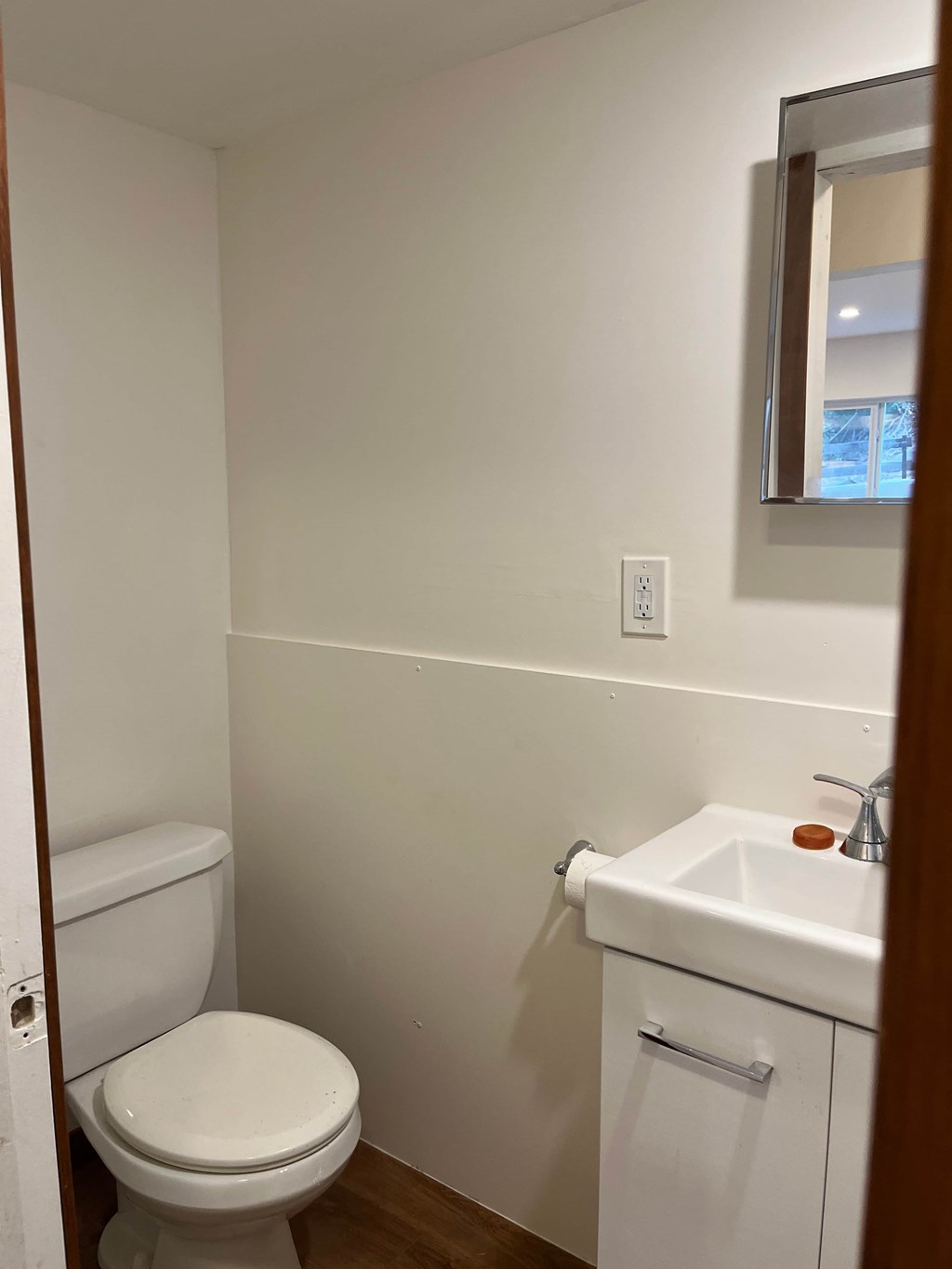 A white toilet sits next to a white sink in a small bathroom.