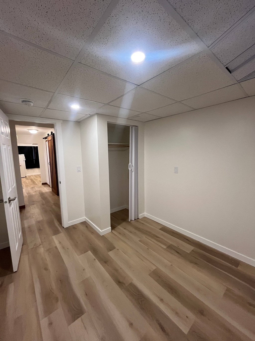 A long hallway with wood floors and white walls.