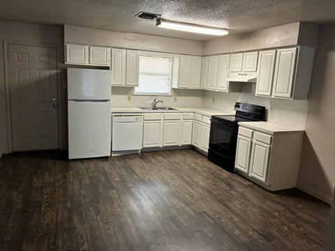 A kitchen with white cabinets and a black stove top oven.