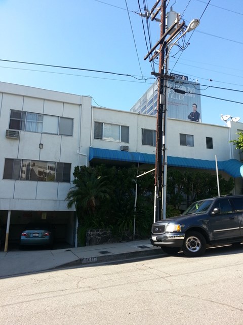 A white building with a blue awning and a grey truck parked in front.