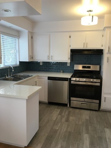 A kitchen with white cabinets and a black backsplash.
