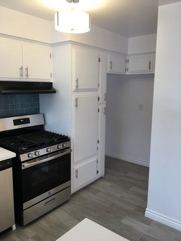 A kitchen with a black stove top oven and white cabinets.