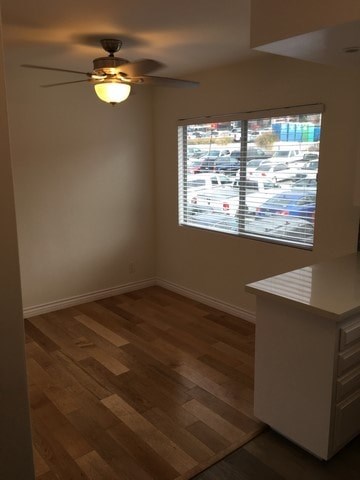 A room with a ceiling fan and a window overlooking a parking lot.