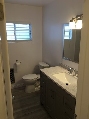A bathroom with a toilet, sink, and mirror.