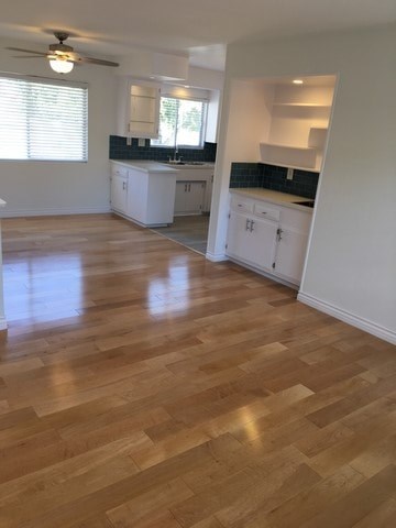 A kitchen with white cabinets and a wooden floor.