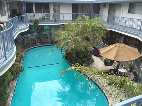A small pool surrounded by a balcony and trees.