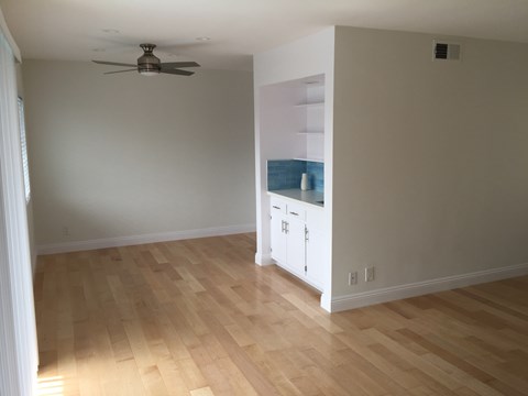 A room with a ceiling fan and wooden flooring.