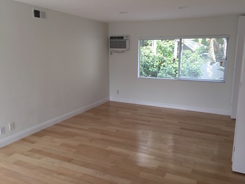 A room with wooden flooring and a window with blinds.