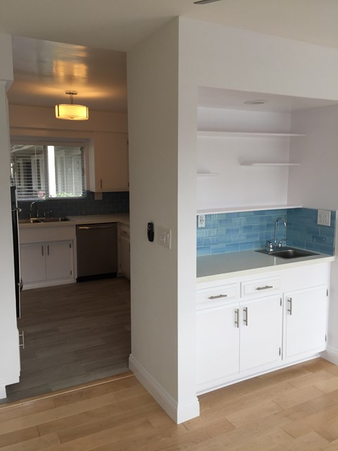 A kitchen with white cabinets and a blue backsplash.