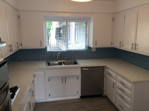 A kitchen with white cabinets and a stainless steel dishwasher.