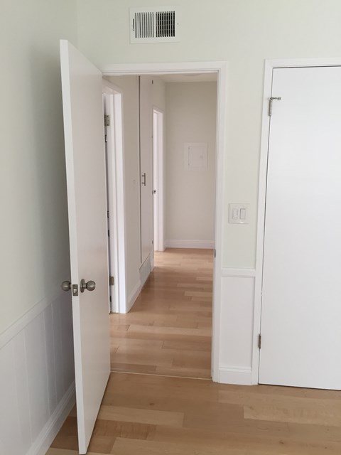 A hallway with white doors and wood floors.