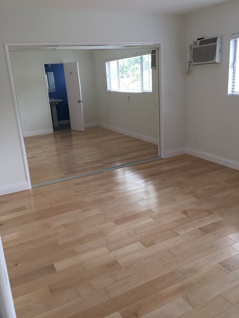 A room with a wooden floor and a mirror on the wall.